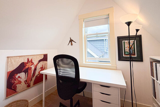 Cozy home office with a white desk, black mesh chair, and a window overlooking neighboring rooftops. - 3752 West 23rd Avenue, Vancouver West Side