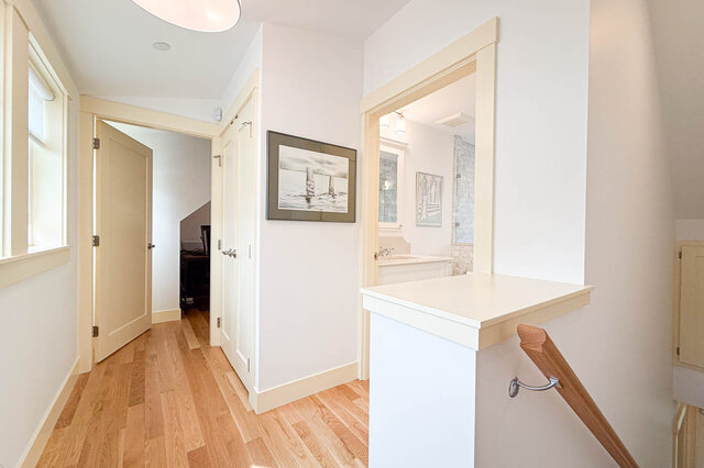 Bright hallway landing with light hardwood floors, white countertop ledge, and framed sailboat art. - 3752 West 23rd Avenue, Vancouver West Side