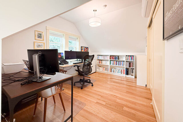 Home office with hardwood floors, sloped ceilings, and a built-in bookshelf lined with books. - 3752 West 23rd Avenue, Vancouver West Side