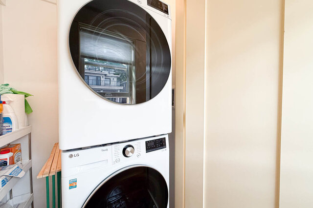 Compact laundry nook with a stacked LG washer and dryer and a small shelving unit holding cleaning supplies.