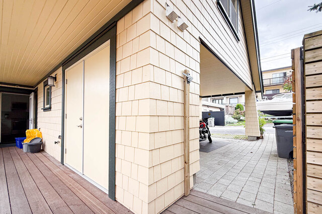Laneway exterior with wooden deck, cream shingled walls, and paved driveway leading to a covered garage. - 3752 West 23rd Avenue, Vancouver West Side
