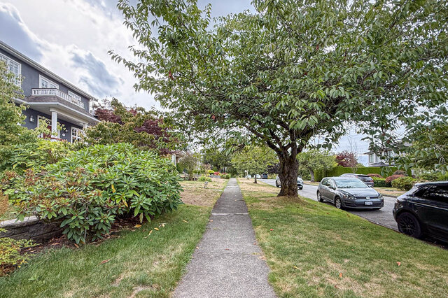 Lush landscaped exterior with a concrete walkway, mature tree, and manicured lawn beside a quiet street. - 3752 West 23rd Avenue, Vancouver West Side