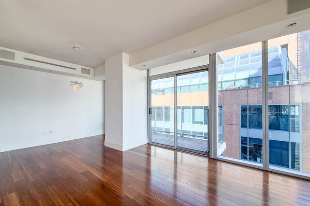 Spacious living room with glossy hardwood floors and floor-to-ceiling windows framing the downtown view. - 2702-667 Howe Street, Vancouver Downtown