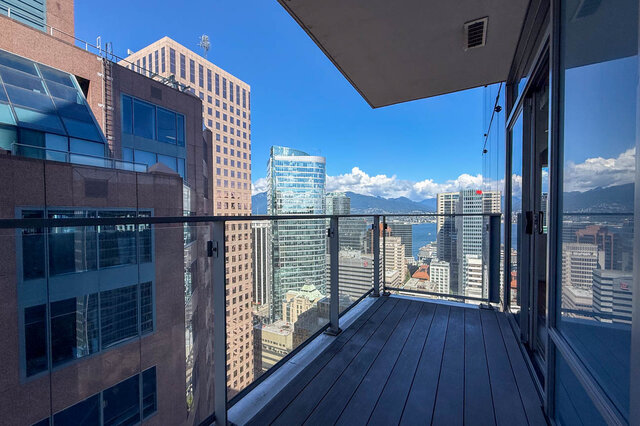 Balcony with dark wood decking and glass railing overlooking a panoramic downtown city view. - 2702-667 Howe Street, Vancouver Downtown