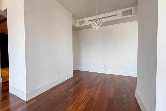 Spacious living room with dark hardwood floors and a crystal chandelier. - 2702-667 Howe Street, Vancouver Downtown