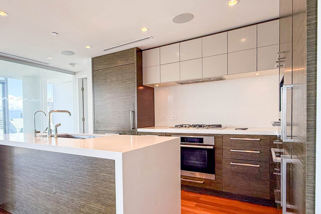 Modern kitchen with white countertops, dark wood cabinetry, and hardwood floors. - 2702-667 Howe Street, Vancouver Downtown