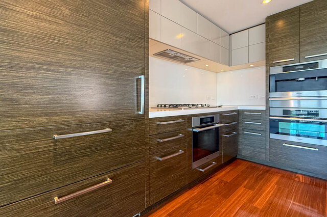 Modern kitchen with dark wood cabinetry, stainless steel ovens, and glossy hardwood floors. - 2702-667 Howe Street, Vancouver Downtown