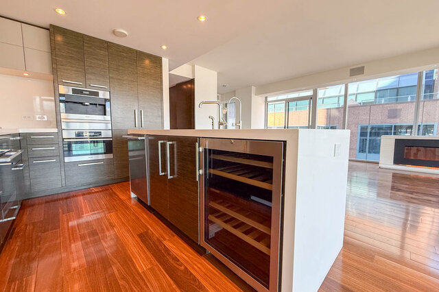 Modern kitchen with dark wood cabinetry, built-in wine cooler, stainless ovens, and hardwood floors. - 2702-667 Howe Street, Vancouver Downtown