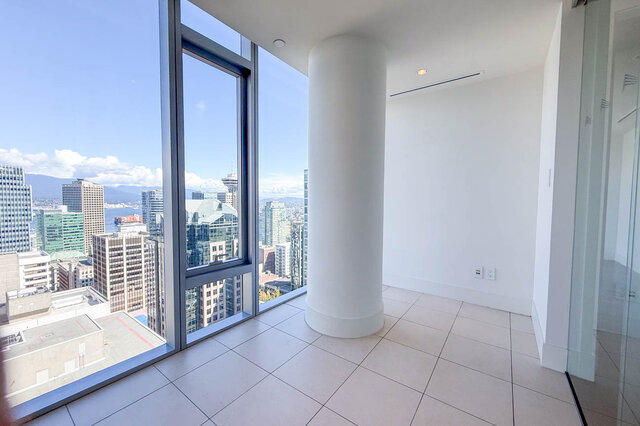 Spacious living area with floor-to-ceiling windows, white tile floors, and a panoramic city and mountain view.