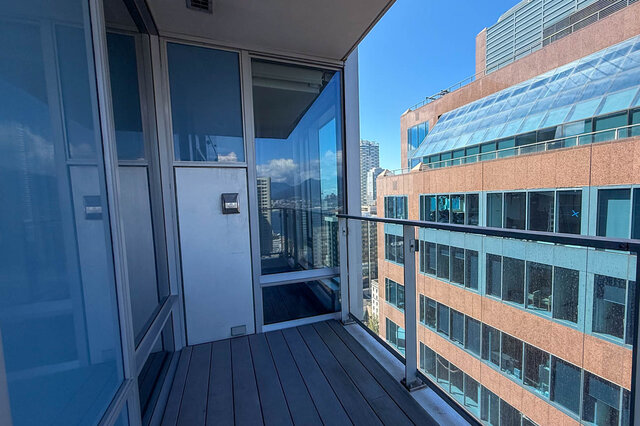Spacious balcony with wood-look decking and glass railings overlooking the city skyline and mountains. - 2702-667 Howe Street, Vancouver Downtown