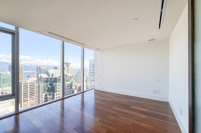 Spacious living room with dark hardwood floors and floor-to-ceiling windows framing a downtown city view. - 2702-667 Howe Street, Vancouver Downtown