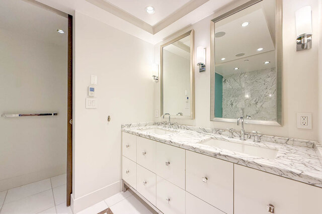 Bright bathroom vanity with white cabinetry, marble countertops, and dual mirrors with sconce lighting. - 2702-667 Howe Street, Vancouver Downtown
