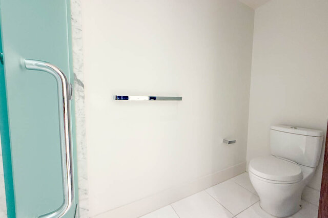 Clean powder room with white tile flooring, a chrome towel bar, and a mint-green door with a sleek handle. - 2702-667 Howe Street, Vancouver Downtown