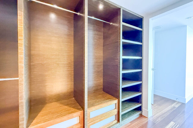 Walk-in closet with wood-grain cabinetry, built-in shelving, and drawers over hardwood floors. - 2702-667 Howe Street, Vancouver Downtown