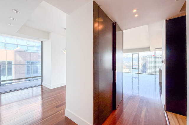 Spacious interior with dark hardwood floors and floor-to-ceiling windows framing a downtown city view. - 2702-667 Howe Street, Vancouver Downtown