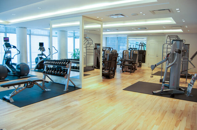 Spacious fitness room with light hardwood floors, a full-length mirror wall, and a full dumbbell rack. - 2702-667 Howe Street, Vancouver Downtown