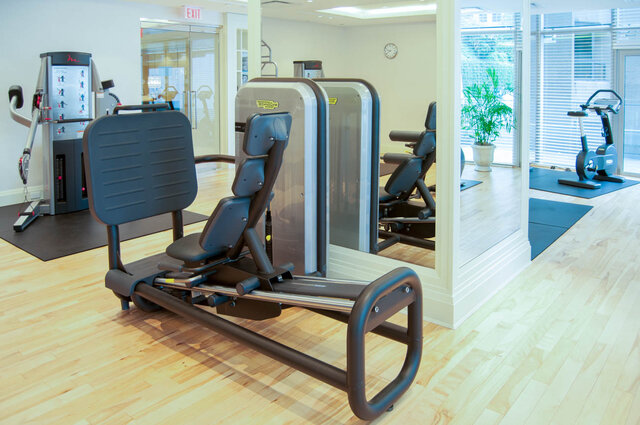 Home gym with a Technogym weight machine, light hardwood floors, and a mirrored wall. - 2702-667 Howe Street, Vancouver Downtown