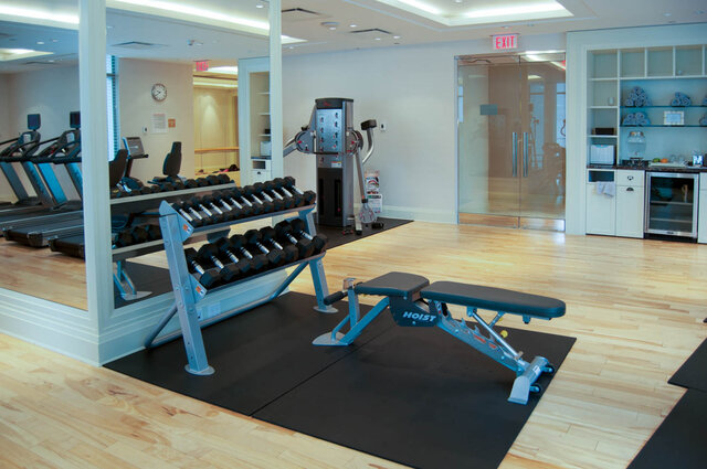 Home gym with hardwood floors, dumbbell racks, and a weight bench beside a mirrored wall. - 2702-667 Howe Street, Vancouver Downtown