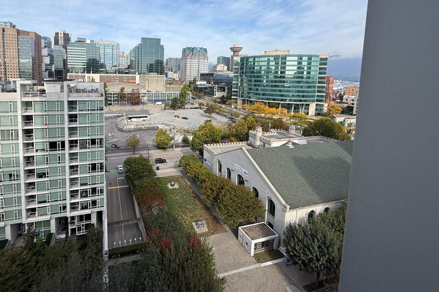 City view overlooking a downtown skyline with a glass high-rise and open parking lot below. - 1603-668 Citadel Parade, Vancouver Downtown