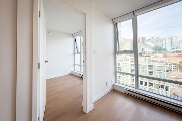 Bright kitchen with white cabinetry, light countertops, and a wooden dining table with two chairs. - 1603-668 Citadel Parade, Vancouver Downtown