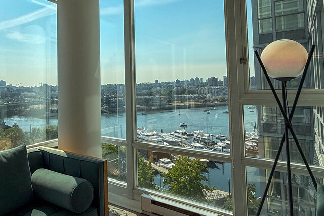 Bright living room with floor-to-ceiling windows, a globe floor lamp, and a marina waterfront view.