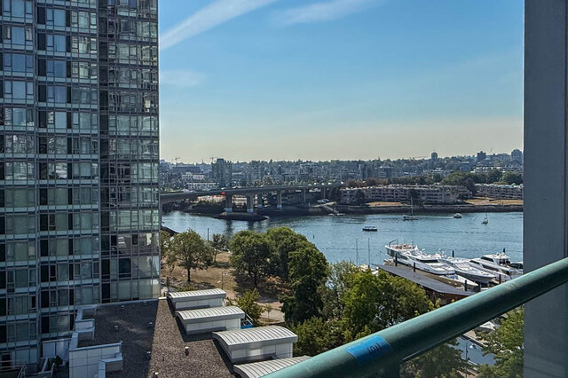 Balcony offering a wide water view over a marina of white yachts and a distant bridge under a clear blue sky.