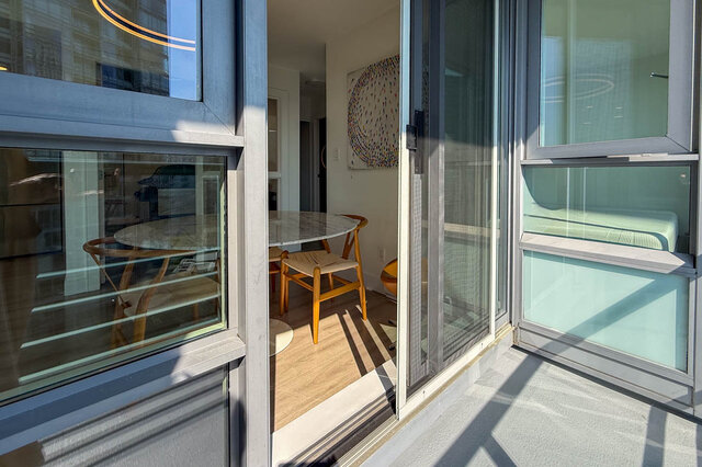 Dining area with a marble-top table, wooden chairs, and hardwood floors opening to a balcony. - 1101-1067 Marinaside Crescent, Vancouver Downtown