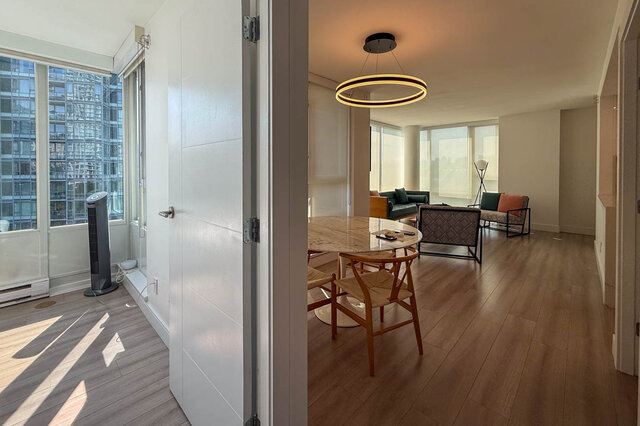Dining area with a round marble table, wooden chairs, ring pendant light, hardwood floors, and high-rise city views.