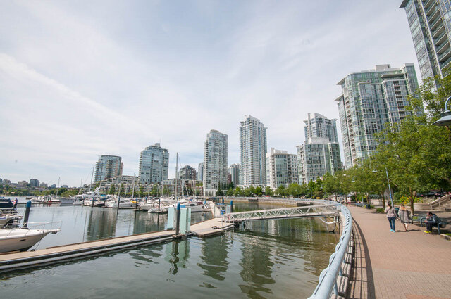 Marina view featuring docked sailboats and a waterfront promenade framed by downtown high-rise towers.