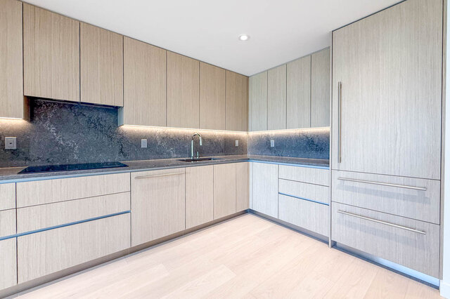 Modern kitchen with light wood-grain cabinets, dark marble-look. - 607-777 Harbour Way, North Vancouver