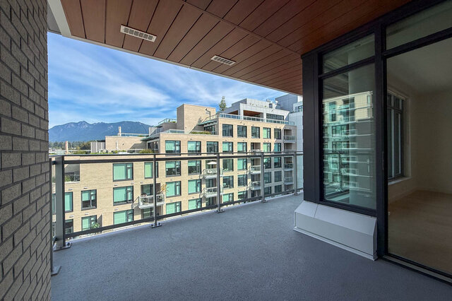 Spacious balcony with wood-paneled ceiling and a clear view of distant mountains. - 607-777 Harbour Way, North Vancouver