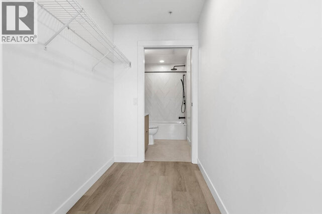 The walk-in closet, a long wire shelf on one wall and a doorway straight through to the bathroom tub. - 504-2268 East Broadway, Vancouver East Side