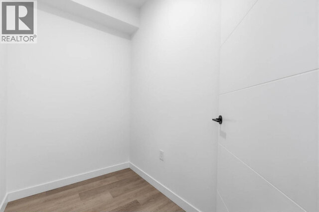 The empty den, white walls, light vinyl plank floors and a white door with a black lever. - 504-2268 East Broadway, Vancouver East Side