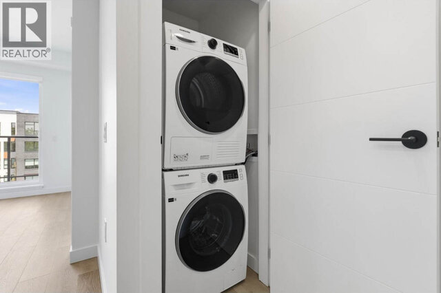 The laundry closet with a stacked Samsung washer and dryer behind a white door, a window onto the neighbouring building beyon