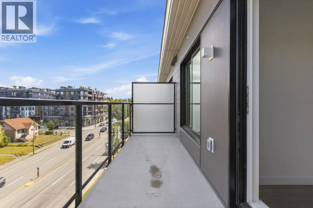 The long private balcony, glass railing along East Broadway, a frosted privacy screen at the far end and the sliding door bac