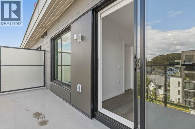 The balcony from the screened end, the sliding door open to the living room and rooftops and treed hills beyond the glass rai