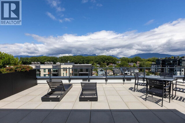Loungers and a dining table on the shared rooftop patio, planters along the edge and the mountains across the whole horizon.