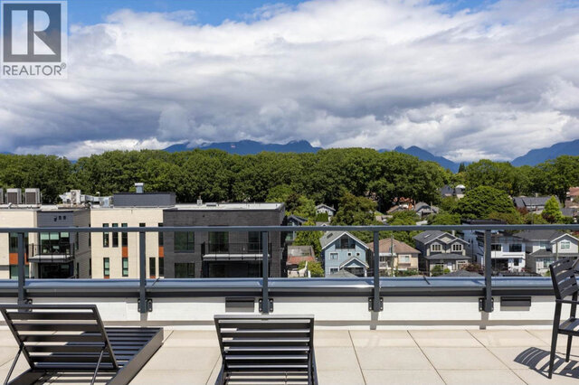 Loungers at the shared rooftop railing, treetops and rooftops below and the mountains beyond. - 504-2268 East Broadway, Vancouver East Side