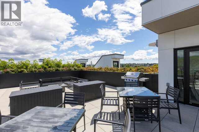 The shared rooftop patio by the lounge doors, a barbecue, dining tables and lounge seating around a fire table.