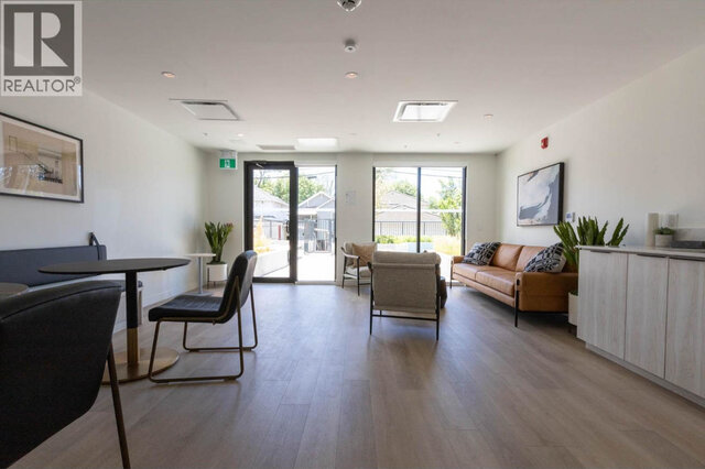 The residents' co-working lounge, a leather sofa and armchairs, cafe tables and glass doors out to the ground-level garden.