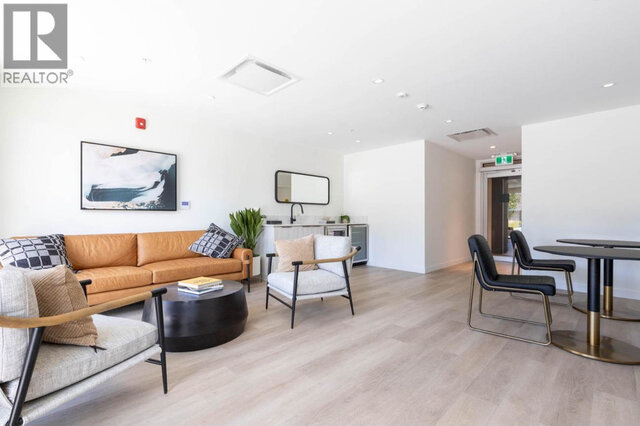 The residents' co-working lounge from the seating end, its kitchenette with a sink against the wall and round tables by the d