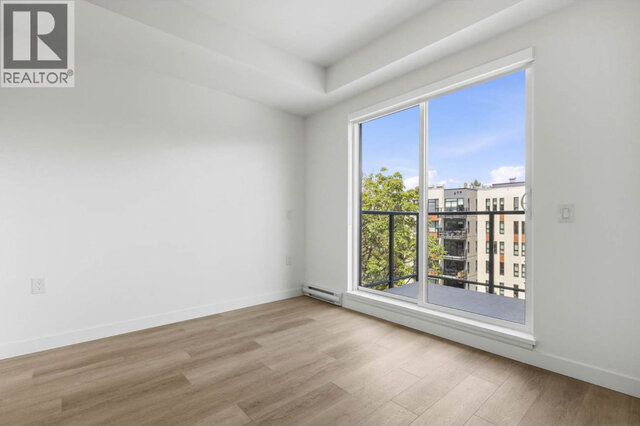 The living room end of the unit, a floor-to-ceiling sliding door out to the balcony under an over-height ceiling, light vinyl