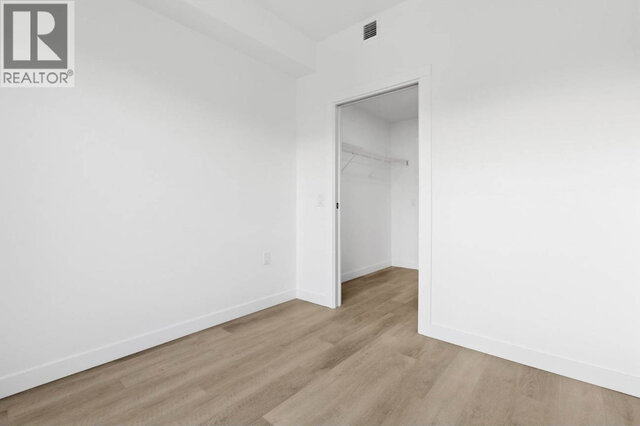 The bedroom looking toward its walk-in closet, the wire shelf visible through the open doorway. - 504-2268 East Broadway, Vancouver East Side