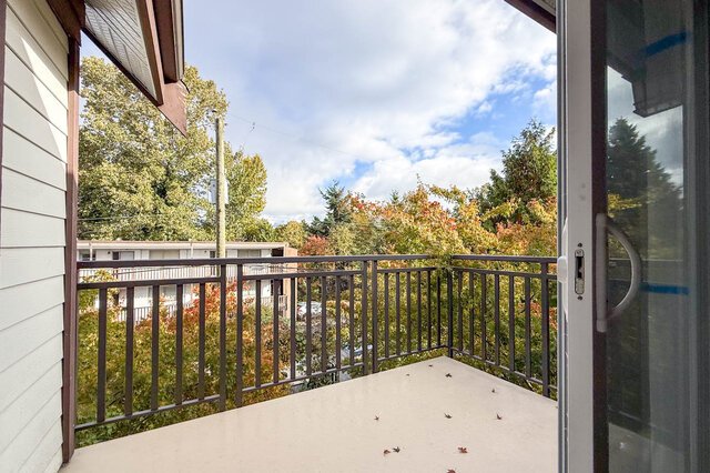 Living room balcony with a metal railing looking out at autumn trees. - 302-1533 East 8th Avenue, Vancouver East Side