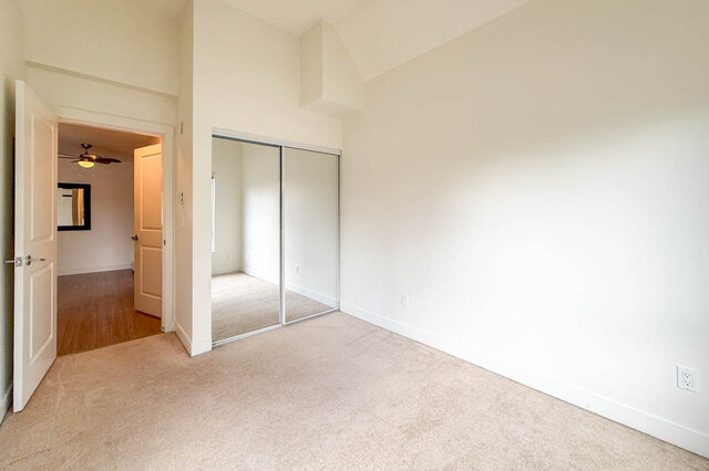 Bedroom with a mirrored closet, carpet and a high ceiling, the door open to the living room. - 302-1533 East 8th Avenue, Vancouver East Side