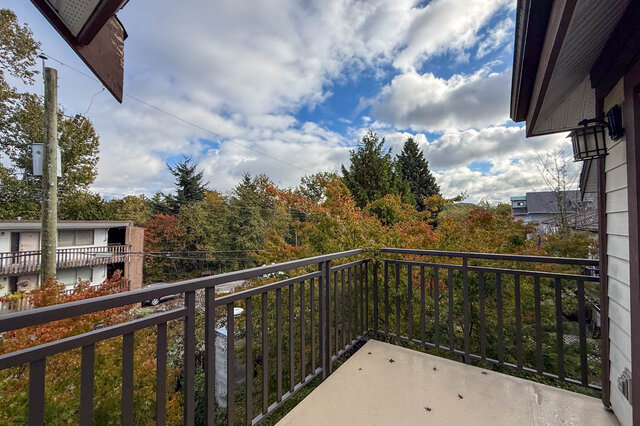 Balcony looking out over treetops in autumn colour under a cloudy blue sky. - 302-1533 East 8th Avenue, Vancouver East Side