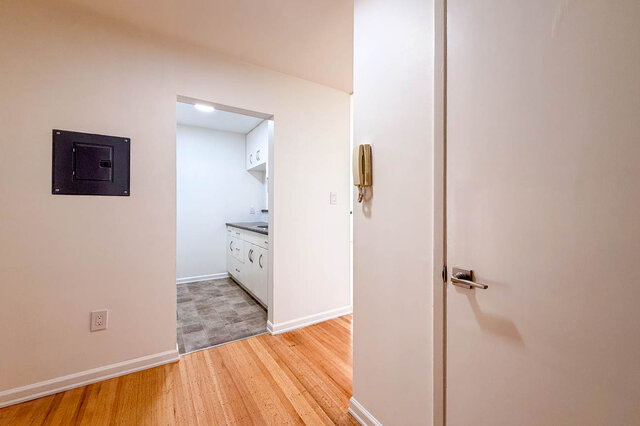 The entry by the front door with an intercom, looking into the kitchen, on hardwood floors - 107-461-16th Street West, North Vancouver