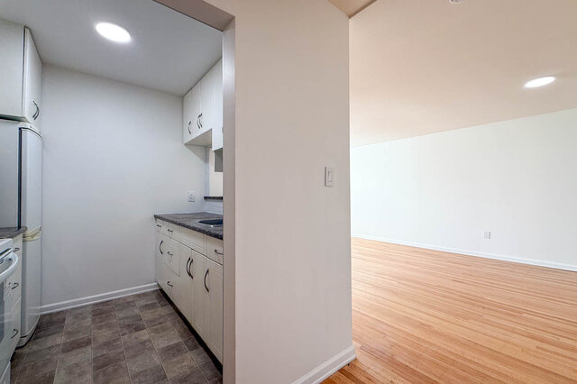 The separate kitchen beside the opening into the bright living room with hardwood floors - 107-461-16th Street West, North Vancouver