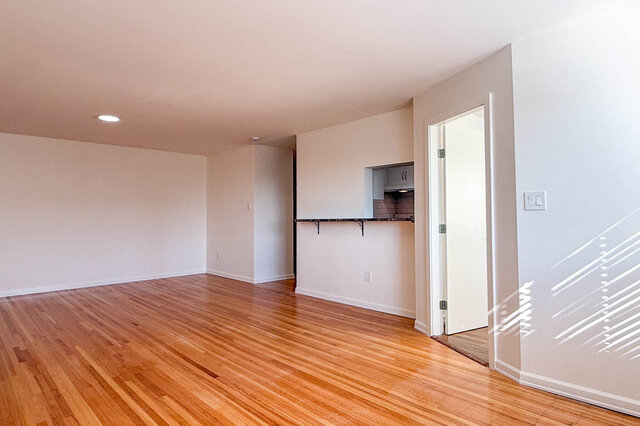 The living room with the pass-through counter and a bedroom door, on hardwood floors - 107-461-16th Street West, North Vancouver