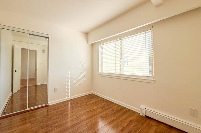 The second bedroom with a mirrored closet and a window with blinds - 107-461-16th Street West, North Vancouver